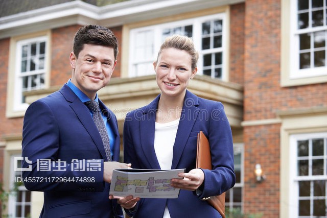 站在住宅物业外面的男女房地产经纪人Male And Female Realtor Standing Outside Residential Property